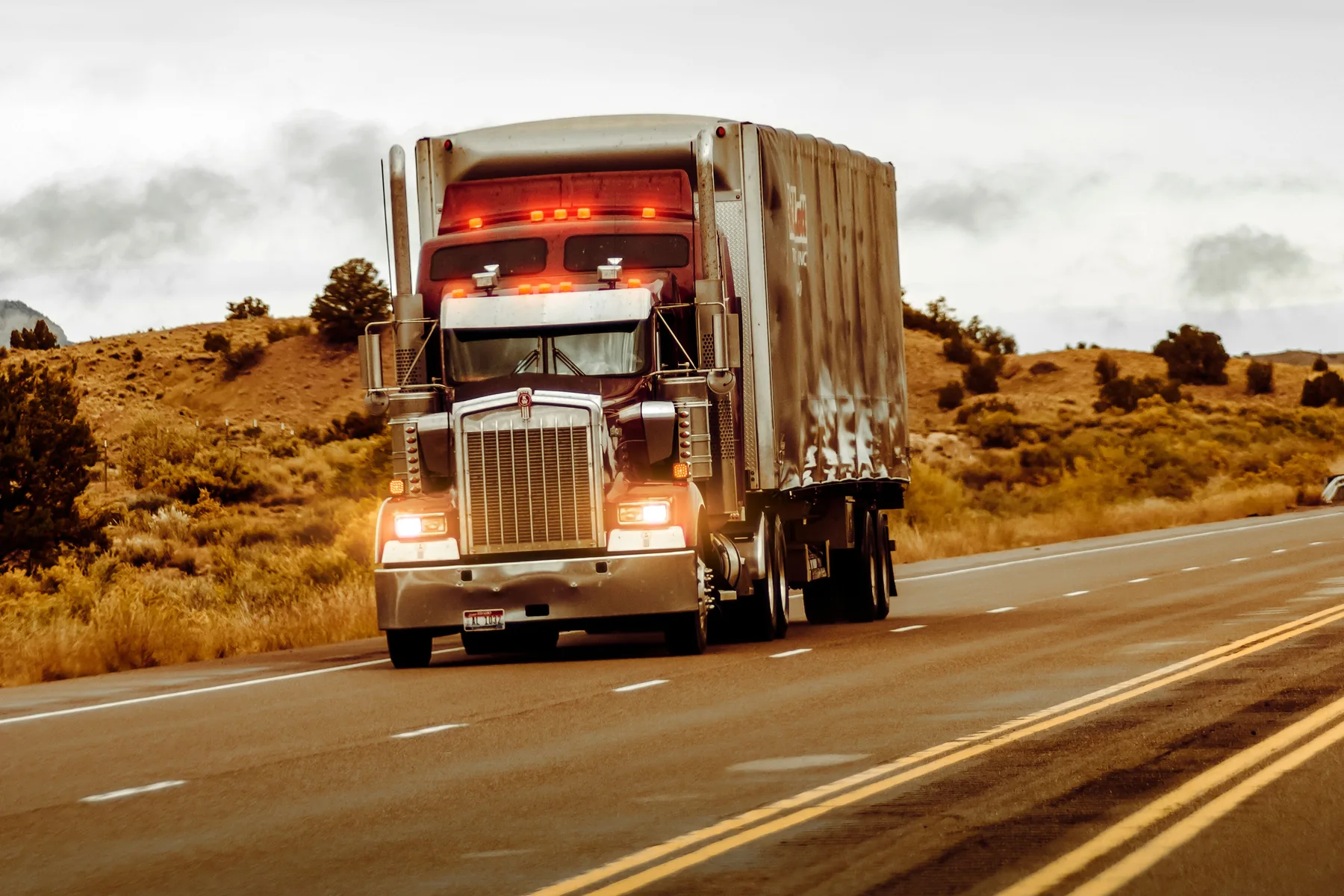 A conventional semi truck carrying freight along an open highway.