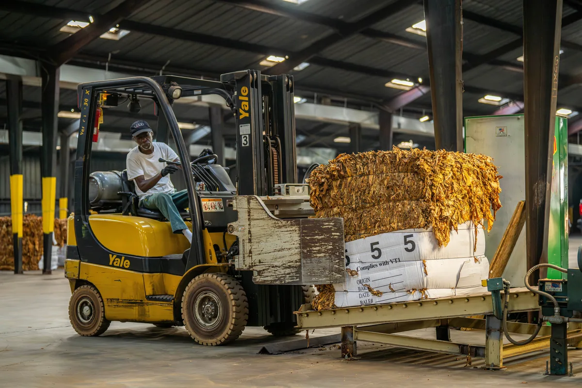 A forklift operator moving packaged material inside an industrial warehouse.