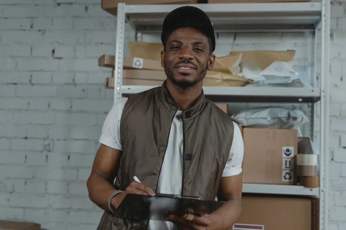 A warehouse worker checking a clipboard among parcels.